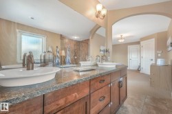 Bathroom featuring a marble finish shower, double vanity, and light colored carpet - 