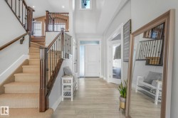 Foyer with stairway, healthy amount of natural light, light wood-style floors, and high vaulted ceiling - 