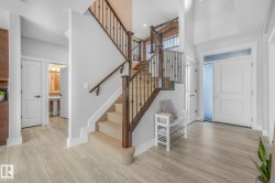 Entryway featuring a towering ceiling, light wood finished floors, and stairway - 