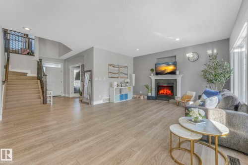 Living room with a tiled fireplace, stairway, light wood-style floors, and recessed lighting - 2307 Rutherford Way, Edmonton, AB - Indoor Photo Showing Living Room With Fireplace