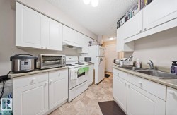 Kitchen featuring white cabinets, white appliances, light countertops, and a textured ceiling - 