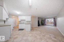 Kitchen with open floor plan, white cabinets, a textured ceiling, light countertops, and light carpet - 