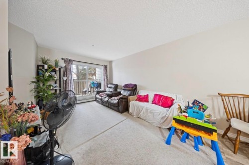 Carpeted living room featuring a textured ceiling - 103 12110 119 Ave, Edmonton, AB - Indoor