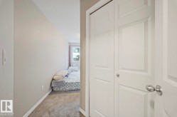 Hallway with light colored carpet and a textured ceiling - 