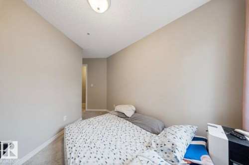 Bedroom with a textured ceiling and carpet flooring - 103 12110 119 Ave, Edmonton, AB - Indoor Photo Showing Bedroom