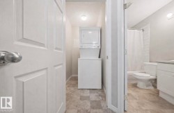 Bathroom featuring vanity, stacked washer and dryer, shower / bathtub combination with curtain, and a textured ceiling - 