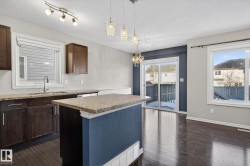 Kitchen with dark wood finished floors, a textured ceiling, dark wood finish cabinets, a chandelier, and a center island - 