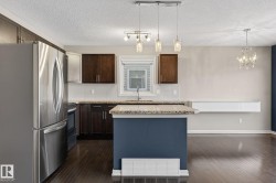 Kitchen with stainless steel appliances, decorative backsplash, dark wood-type flooring, light stone countertops, and a center island - 