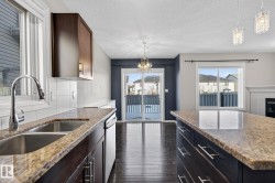 Kitchen featuring light stone countertops, dark wood-type flooring, a tile fireplace, suspended lighting, and a textured ceiling - 