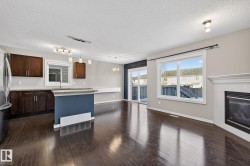 Kitchen with dark wood finish cabinetry, a center island, a textured ceiling, a tiled fireplace, and freestanding refrigerator - 