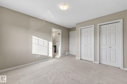 Unfurnished bedroom featuring two closets, carpet floors, ensuite bath, and a textured ceiling - 