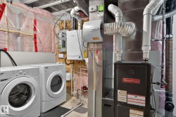 Laundry room featuring tankless water heater, electric panel, heating unit, concrete floors, and independent washer and dryer - 