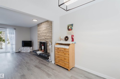 Living room with light wood-style floors and a large fireplace - 10423 35 Avenue, Edmonton, AB - Indoor Photo Showing Other Room With Fireplace