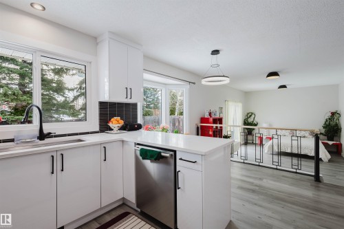 Kitchen with dishwasher, white cabinets, a peninsula, pendant lighting, and light wood finished floors - 10423 35 Avenue, Edmonton, AB - Indoor Photo Showing Kitchen