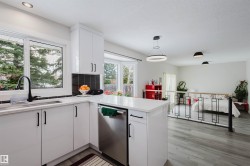 Kitchen with dishwasher, white cabinets, a peninsula, pendant lighting, and light wood finished floors - 
