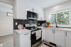 Kitchen with stainless steel appliances, white cabinetry, light wood-style flooring, recessed lighting, and backsplash - 
