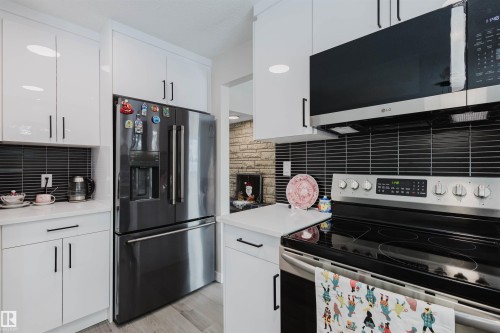 Kitchen featuring stainless steel appliances, white cabinets, light countertops, and light wood-type flooring - 10423 35 Avenue, Edmonton, AB - Indoor Photo Showing Kitchen