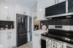 Kitchen featuring stainless steel appliances, white cabinets, light countertops, and light wood-type flooring - 