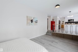 Bedroom featuring light wood finished floors and stainless steel fridge with ice dispenser - 