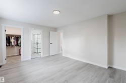 Unfurnished bedroom with a spacious closet, light wood finished floors, and ensuite bathroom - 