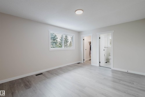 Unfurnished bedroom with a walk in closet, light wood finished floors, and ensuite bath - 10423 35 Avenue, Edmonton, AB - Indoor Photo Showing Other Room
