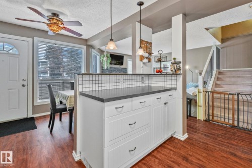Kitchen featuring white cabinets, a textured ceiling, pendant lighting, dark wood finished floors, and a ceiling fan - 3 1820 56 Street, Edmonton, AB - Indoor