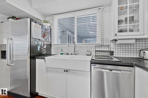 Kitchen with dark countertops, stainless steel appliances, and white cabinetry - 3 1820 56 Street, Edmonton, AB - Indoor Photo Showing Kitchen