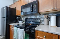 Kitchen featuring black appliances, backsplash, and wood finish cabinets - 
