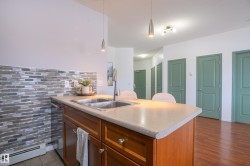 Kitchen featuring a peninsula, wood finish cabinetry, baseboard heating, decorative backsplash, and hanging light fixtures - 