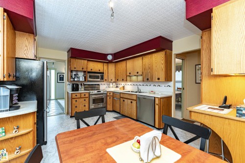 Kitchen featuring light countertops, stainless steel appliances, wood finish cabinetry, light floors, and open shelves - 2112 67 Street Nw, Edmonton, AB - Indoor Photo Showing Kitchen