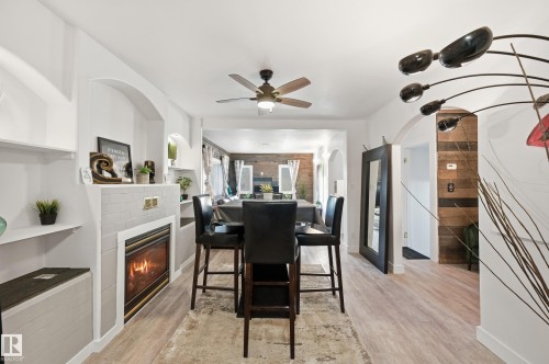 Dining room with a glass covered fireplace, light wood-style flooring, ceiling fan, and arched walkways - 10656 93 Street, Edmonton, AB - Indoor Photo Showing Dining Room