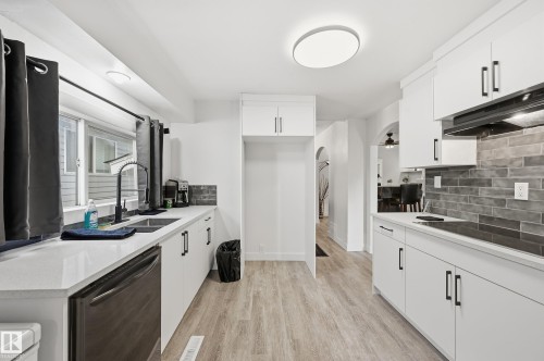 Kitchen featuring dishwasher, arched walkways, ventilation hood, white cabinetry, and light wood-type flooring - 10656 93 Street, Edmonton, AB - Indoor Photo Showing Kitchen With Double Sink