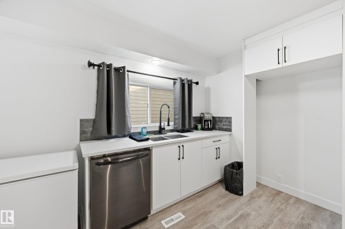 Kitchen with white cabinets, stainless steel dishwasher, and light wood-style floors - 10656 93 Street, Edmonton, AB - Indoor Photo Showing Kitchen With Double Sink