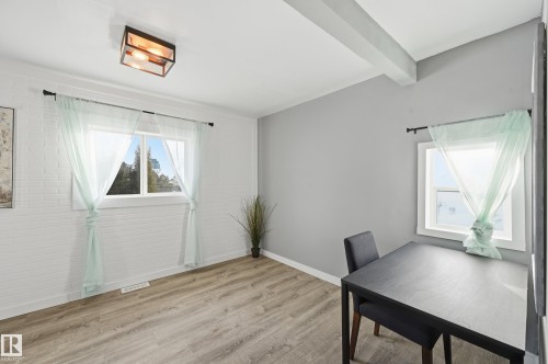 Unfurnished office featuring light wood finished floors, beamed ceiling, and brick wall - 10656 93 Street, Edmonton, AB - Indoor