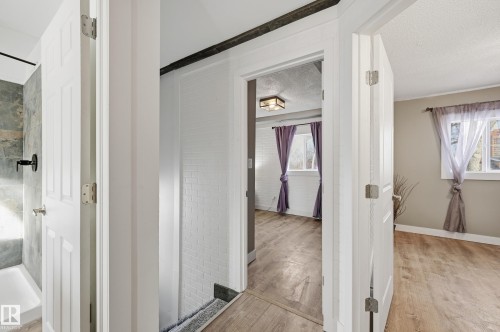 Bathroom featuring light wood-style flooring, a textured ceiling, and a tile shower - 10656 93 Street, Edmonton, AB - Indoor Photo Showing Other Room