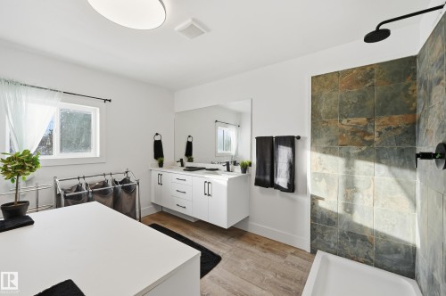 Bathroom featuring a freestanding bath, double vanity, light wood-type flooring, and a tile shower - 10656 93 Street, Edmonton, AB - Indoor