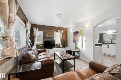 Living room featuring wooden walls, an accent wall, light wood finished floors, and arched walkways - 10656 93 Street, Edmonton, AB - Indoor Photo Showing Living Room