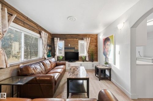 Living room with wood walls, an accent wall, healthy amount of natural light, and light wood-style floors - 10656 93 Street, Edmonton, AB - Indoor Photo Showing Living Room