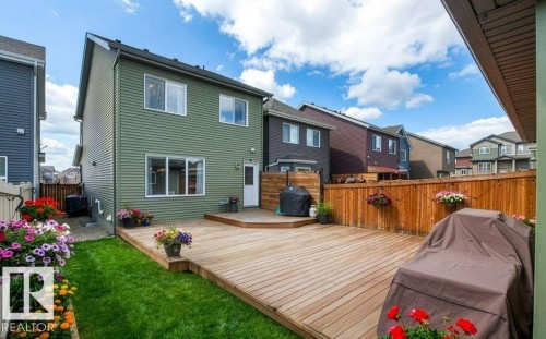 Back of property with a fenced backyard, a wooden deck, and a residential view - 3351 Orchards Link, Edmonton, AB - Outdoor With Deck Patio Veranda With Exterior