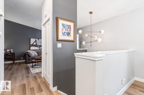 Corridor featuring light wood finished floors and suspended lighting - 6411 180 Street, Edmonton, AB - Indoor Photo Showing Other Room