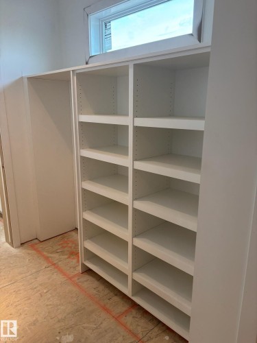 Built-in white shelving unit with adjustable shelves, integrated alongside an open closet space, illuminated by an overhead window - 30 Elsinore Place, Edmonton, AB - Indoor With Storage