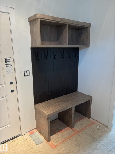 Built-in entryway bench with wood-finish construction, integrated storage cubbies, and a black paneled backboard with five hooks - 30 Elsinore Place, Edmonton, AB - Indoor Photo Showing Other Room