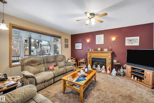 Carpeted living room with a glass covered fireplace, ceiling fan, and an accent wall - 11432 71 Street, Edmonton, AB - Indoor Photo Showing Living Room With Fireplace