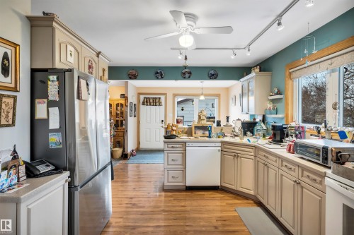 Kitchen with cream cabinetry, freestanding refrigerator, a ceiling fan, light countertops, and a peninsula - 11432 71 Street, Edmonton, AB - Indoor Photo Showing Kitchen