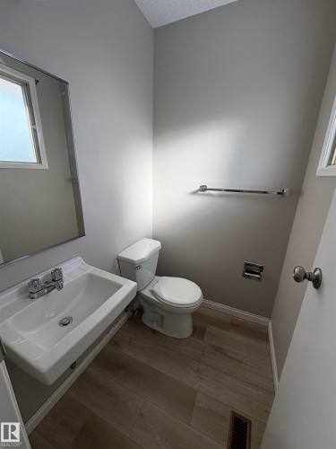 Half bathroom featuring light wood-type flooring and a textured ceiling - Edmonton, AB - Indoor Photo Showing Bathroom