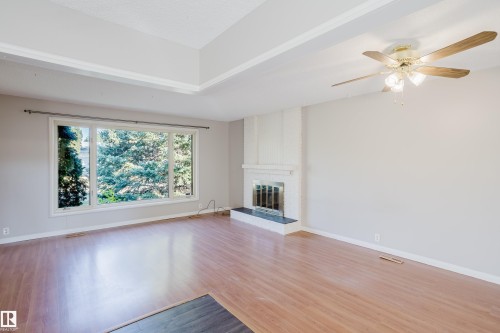 Unfurnished living room with light wood-style floors, a ceiling fan, and a brick fireplace - Edmonton, AB - Indoor With Fireplace