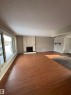 Unfurnished living room with a textured ceiling, dark wood-style flooring, and a brick fireplace - Edmonton, AB  - Indoor Photo Showing Other Room 