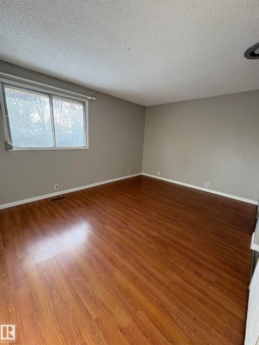 Empty room featuring a textured ceiling and wood finished floors - Edmonton, AB - Indoor Photo Showing Other Room