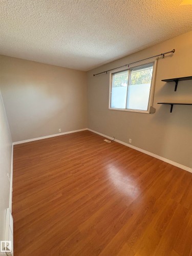 Empty room featuring light wood finished floors and a textured ceiling - Edmonton, AB - Indoor Photo Showing Other Room