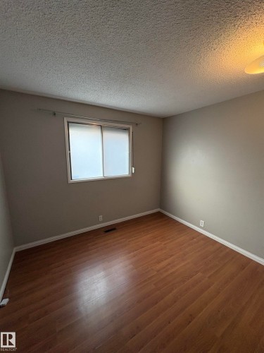 Unfurnished room featuring dark wood-type flooring and a textured ceiling - Edmonton, AB - Indoor Photo Showing Other Room